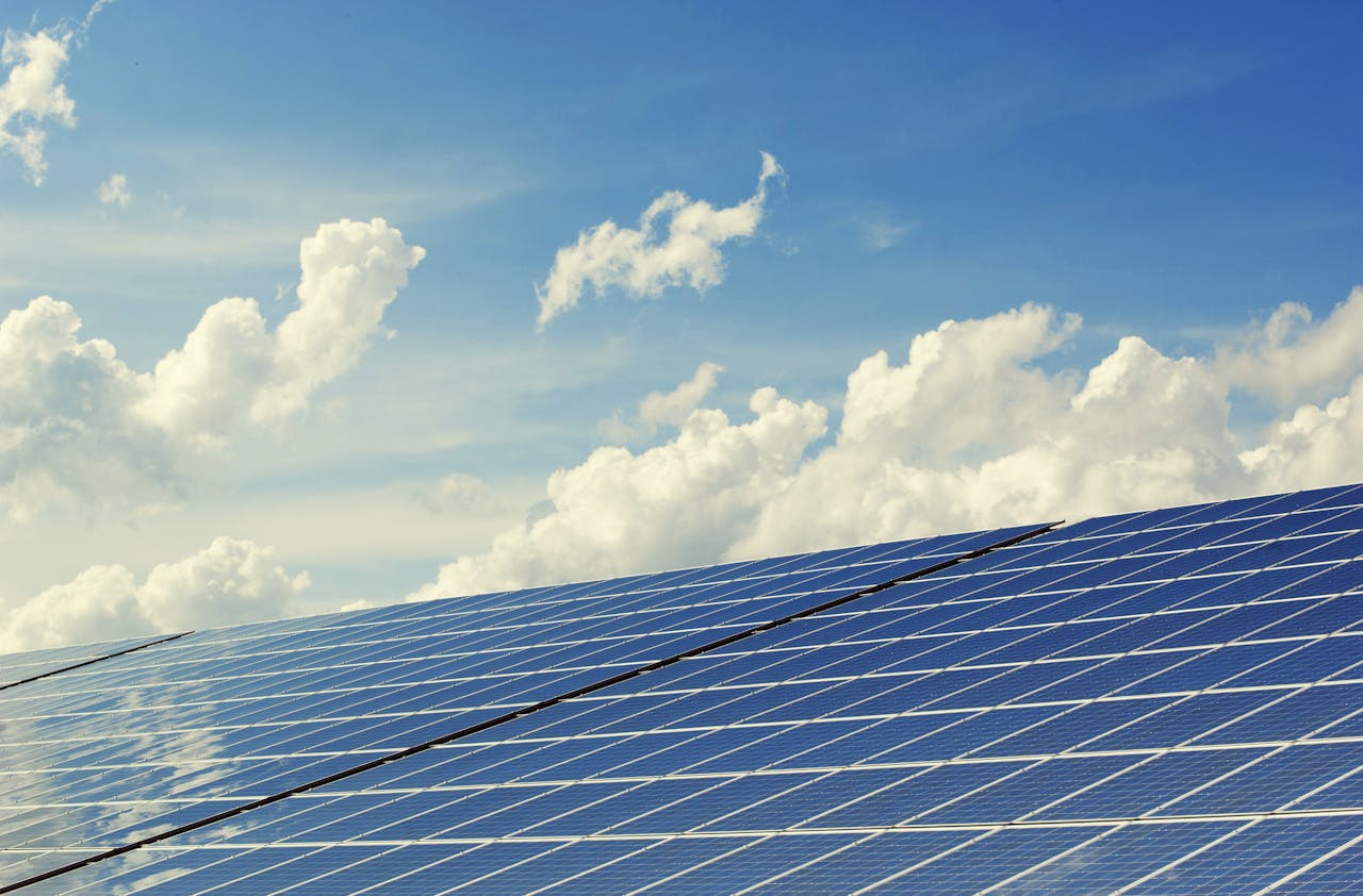 services-02 Sleek modern solar panels under a vibrant blue sky with clouds, symbolizing clean energy.